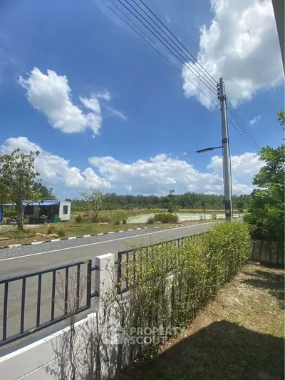 Scenic view of a suburban road with lush greenery and clear blue sky.