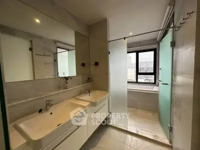 Modern bathroom with dual sinks and glass shower in luxury apartment