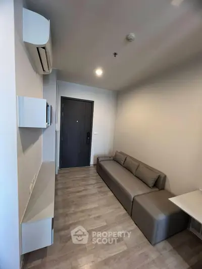 Modern living room with sleek sofa and wall-mounted shelves in a cozy apartment.