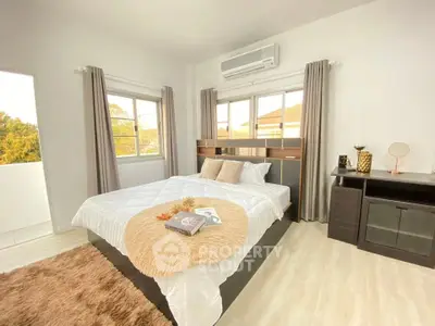 Spacious bedroom with modern decor and large windows offering natural light.