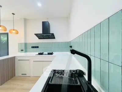 Modern kitchen with sleek design, featuring green tile backsplash and black fixtures.