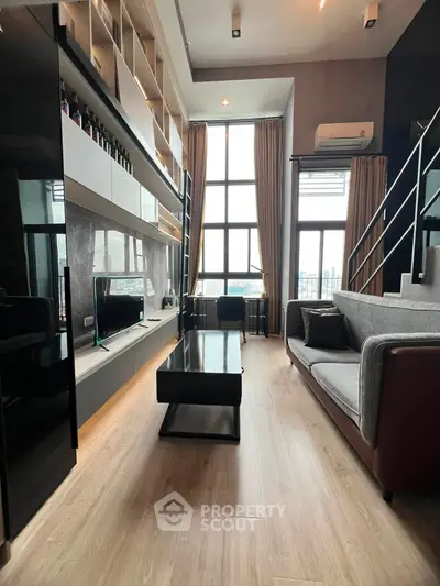 Modern living room with high ceilings and large windows offering city views.