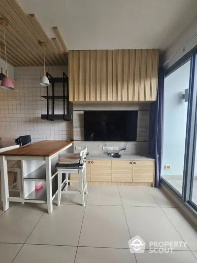 Modern living room with stylish wooden accents and large TV, featuring open layout and balcony access.