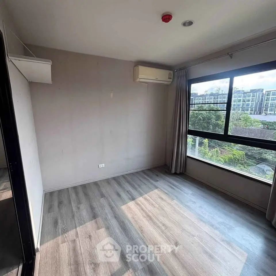 Spacious empty room with large window and air conditioning, perfect for customization.