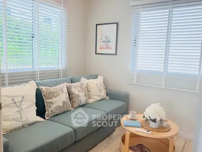 Cozy living room with stylish sofa and natural light from large windows, perfect for relaxation.