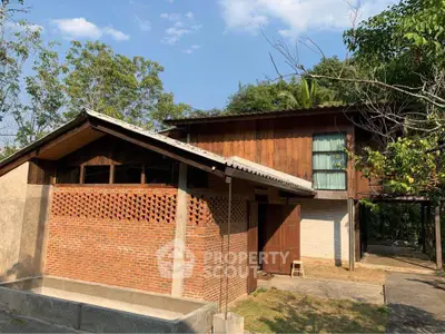 Charming rustic house with brick and wood exterior surrounded by lush greenery.