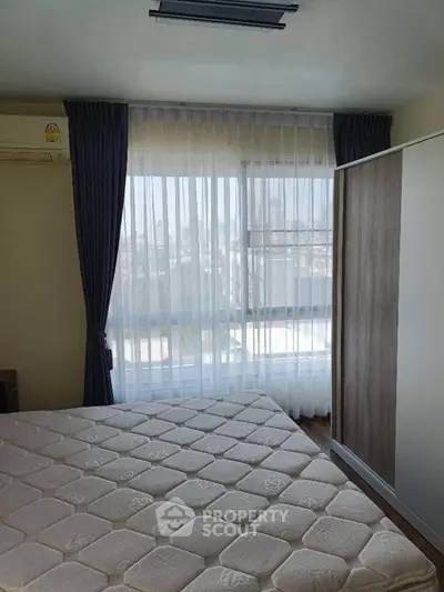 Bright bedroom with large window and modern wardrobe, offering a serene city view.