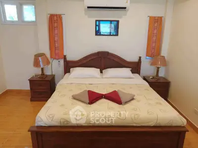 Cozy bedroom with wooden furniture and air conditioning, perfect for relaxation.