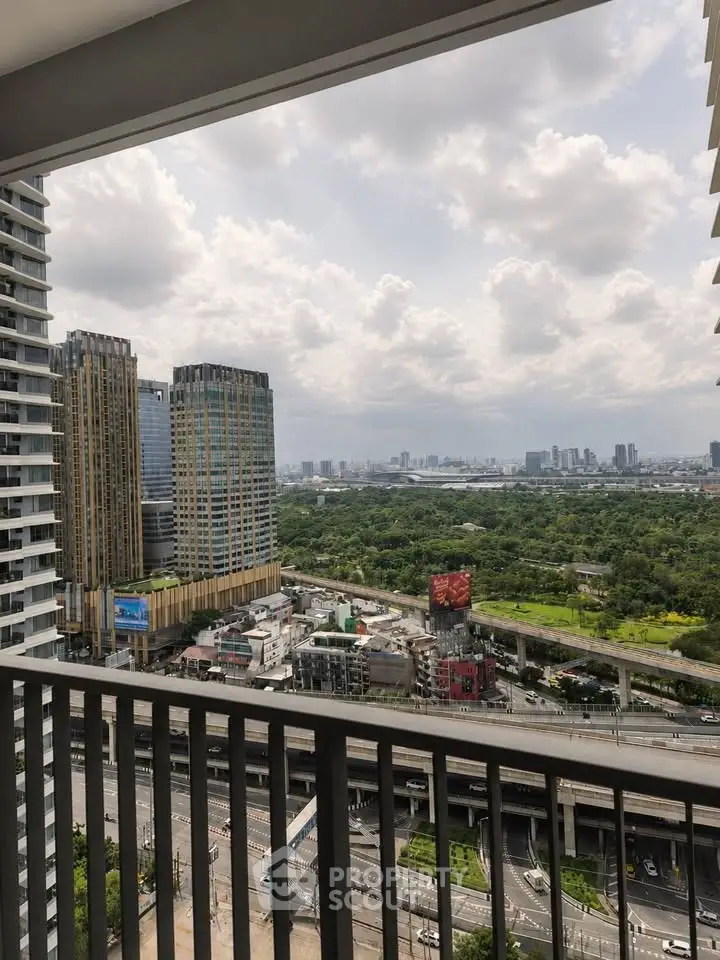 Stunning cityscape view from a high-rise balcony overlooking lush greenery and urban skyline.