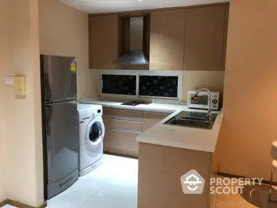 Modern kitchen with sleek appliances and washing machine in compact layout