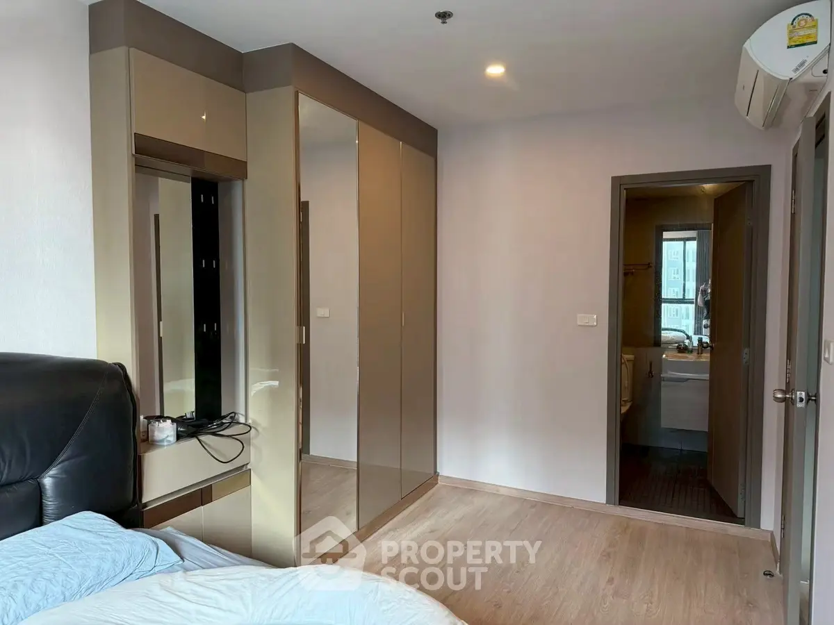 Modern bedroom with sleek wardrobe and ensuite bathroom in a stylish apartment.