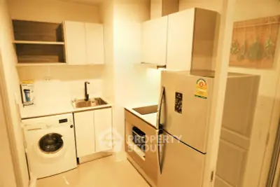 Modern kitchen with sleek appliances and washing machine in compact layout