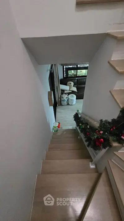 Stylish staircase with festive decor leading to a cozy living area with large windows.