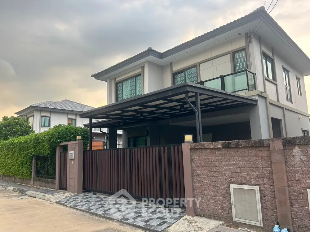 Modern two-story house with gated entrance and spacious driveway in suburban neighborhood.