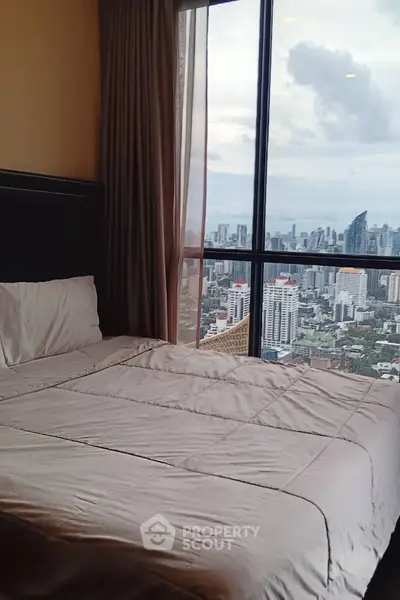Luxurious bedroom with stunning city skyline view from a high-rise window.