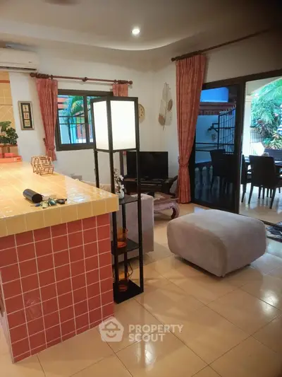 Charming open-plan living room with cozy seating and access to outdoor patio, perfect for relaxation.