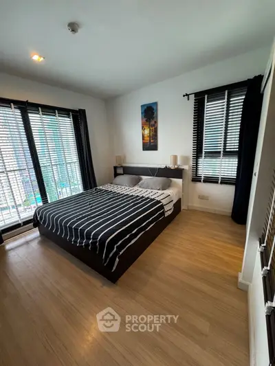Modern bedroom with large windows and stylish decor in urban apartment.