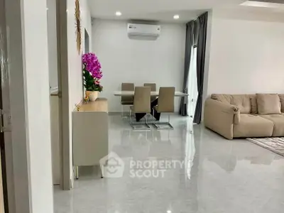 Modern living room with sleek dining area and plush sofa, featuring elegant decor and bright ambiance.