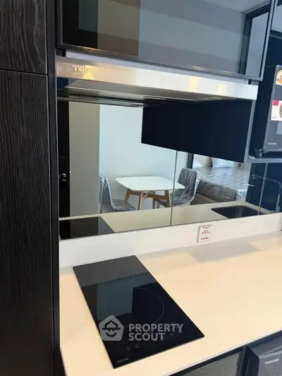 Modern kitchen with sleek black induction cooktop and mirrored backsplash