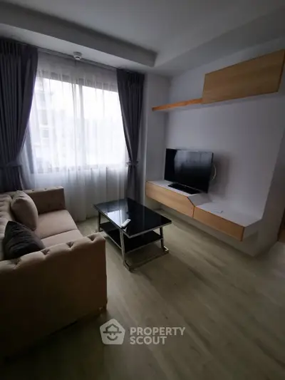 Modern living room with stylish sofa and wall-mounted TV, featuring elegant curtains and wooden flooring.