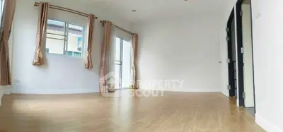Spacious empty room with wooden flooring and large windows, perfect for customization.