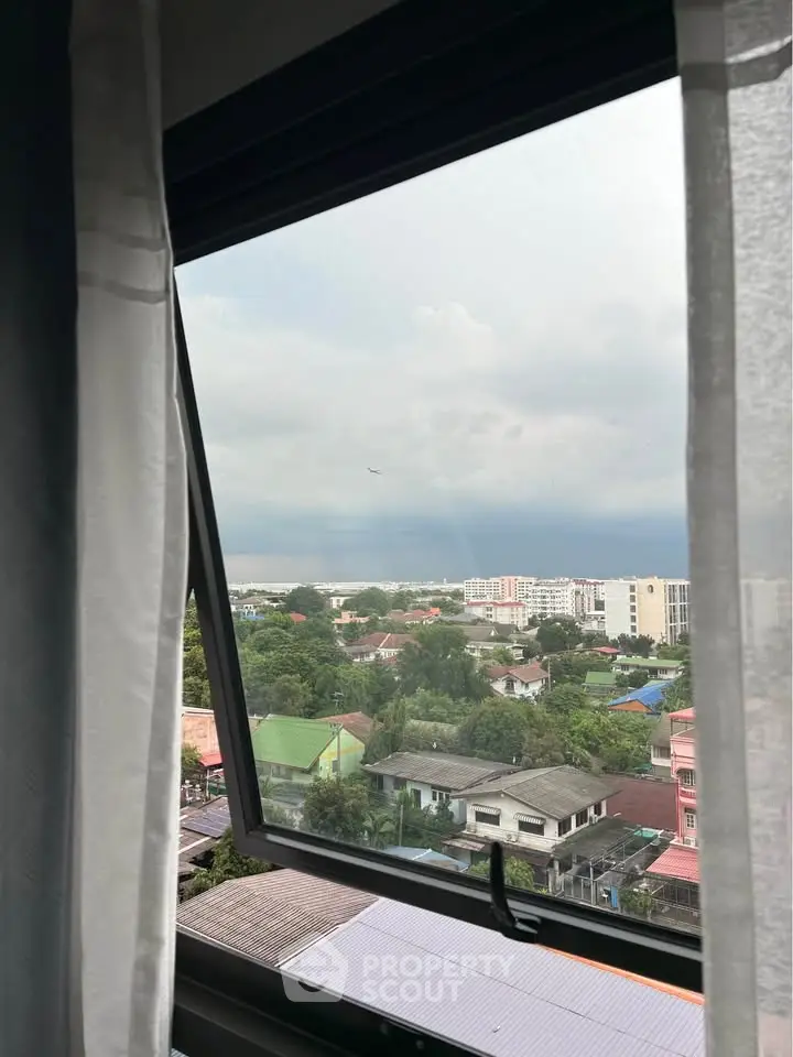 Stunning cityscape view from a window, showcasing urban living with lush greenery and modern buildings.