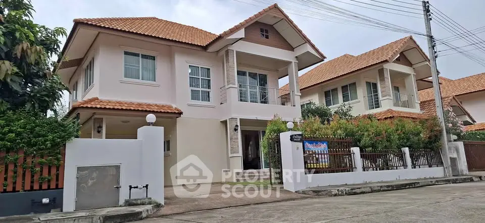 Charming two-story house with red-tiled roof and lush garden in a serene neighborhood.