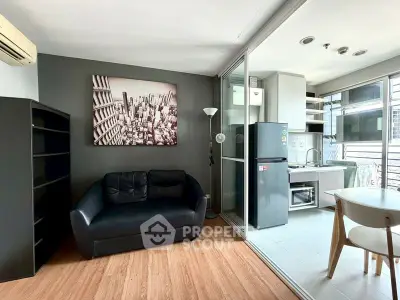 Modern living room with open kitchen, featuring sleek furniture and cityscape artwork.