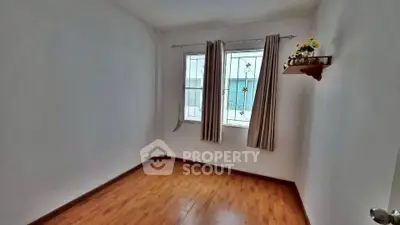 Spacious empty room with wooden flooring and window view, ideal for customization.