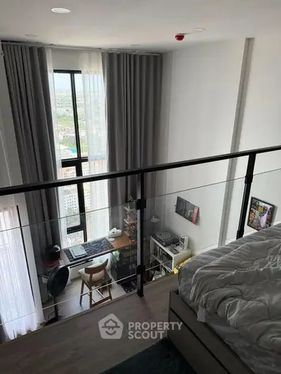 Modern loft bedroom with large window and city view, featuring a cozy workspace and stylish decor.