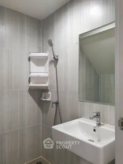 Modern bathroom with sleek fixtures and minimalist design, featuring a shower and sink.