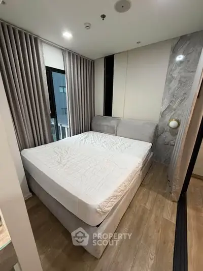 Modern bedroom with stylish decor and large window in a contemporary apartment.