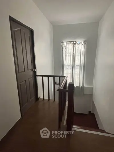 Cozy stairway with wooden railing and natural light from window