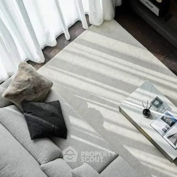 Stylish modern living room with cozy gray sofa and elegant coffee table, bathed in natural light.