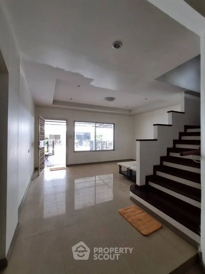 Spacious modern living room with large windows and elegant staircase