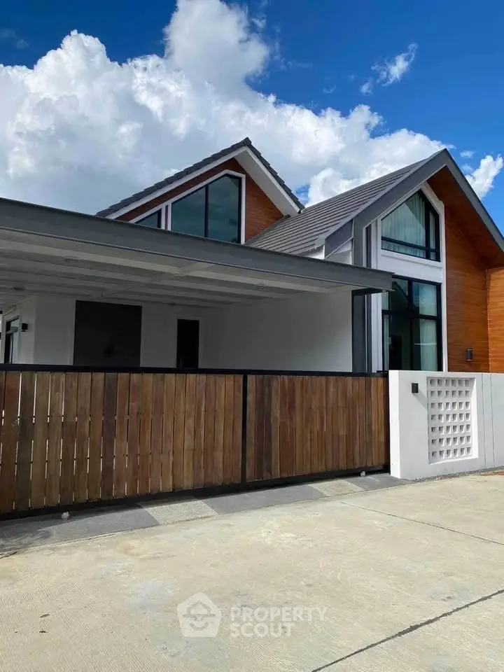 Modern two-story house with wooden accents and large windows under a clear blue sky.