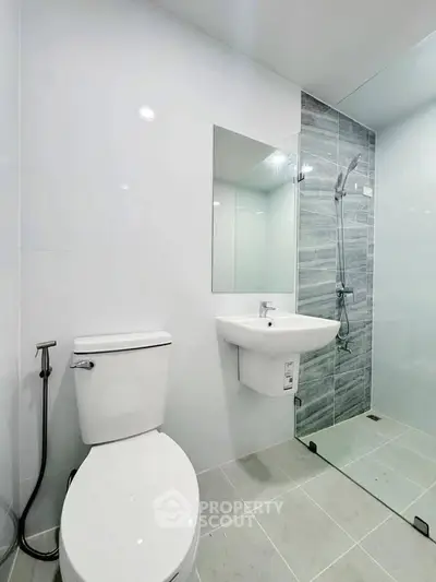 Modern bathroom with sleek design, featuring a shower and toilet in a bright, minimalist space.