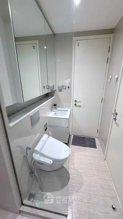 Modern compact bathroom with sleek fixtures and glass partition in a contemporary apartment.