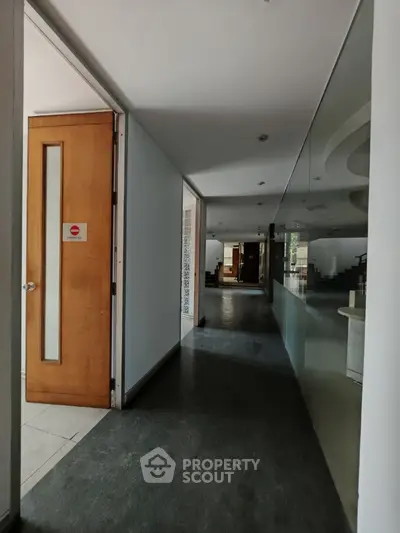 Spacious modern hallway with wooden door and glass wall in commercial building