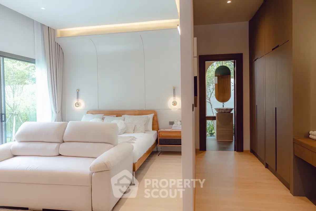 Luxurious bedroom with modern design and garden view, featuring elegant lighting and cozy seating area.