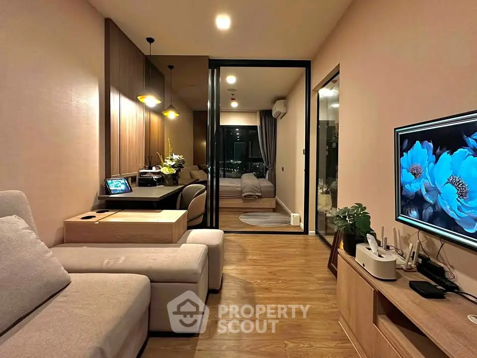 Modern living room with cozy seating and stylish decor, featuring a view into a chic bedroom.