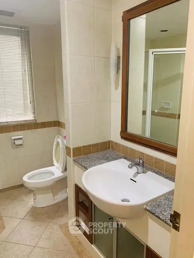 Modern bathroom with sleek fixtures and neutral tiles, featuring a spacious shower and large mirror.