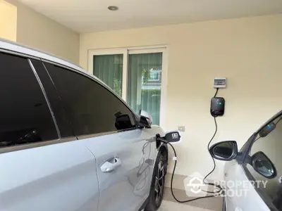 Modern home with electric vehicle charging station in covered parking area.