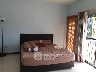 Spacious bedroom with large windows and natural light, featuring a cozy bed and elegant curtains.