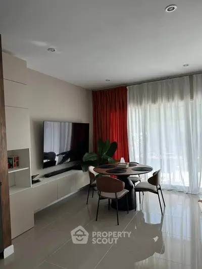 Modern living room with sleek furniture and large TV, featuring elegant curtains and glossy tiled flooring.