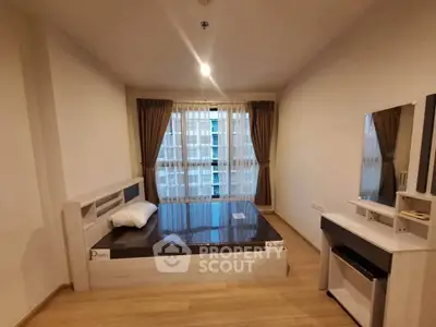 Spacious bedroom with modern furnishings and large window offering natural light in a stylish apartment.