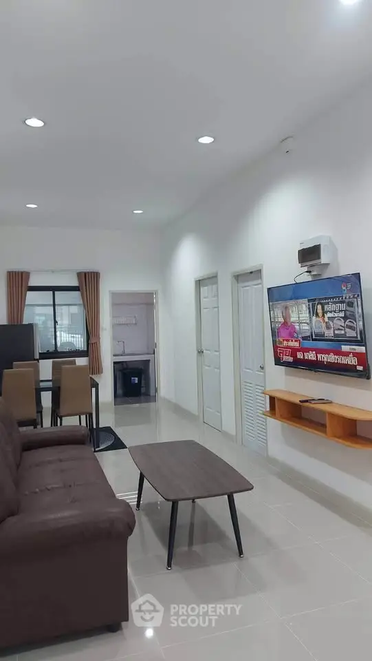 Modern living room with sleek furniture and wall-mounted TV in a bright, open space.