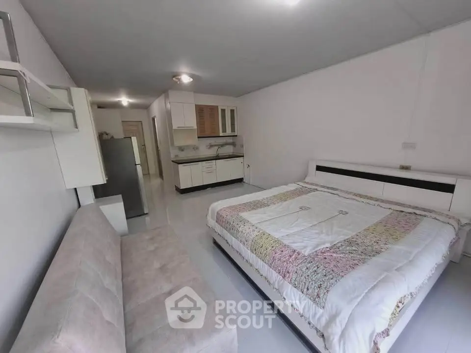 Spacious studio apartment with modern kitchen and cozy bed, ideal for urban living.