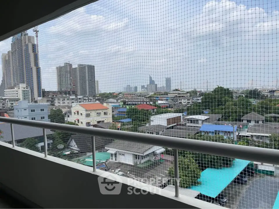 Stunning cityscape view from a high-rise balcony overlooking urban skyline and residential area.