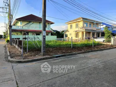 Corner residential plot with potential for development, surrounded by houses in a suburban neighborhood.